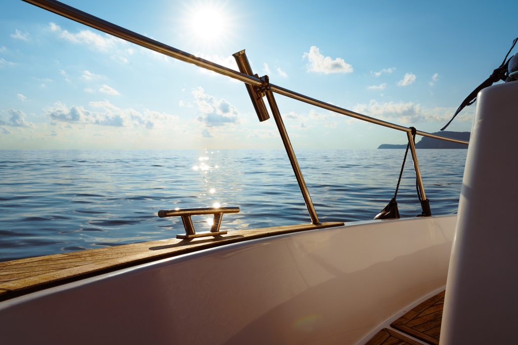 Deck of white yacht sailing in open sea at sunset